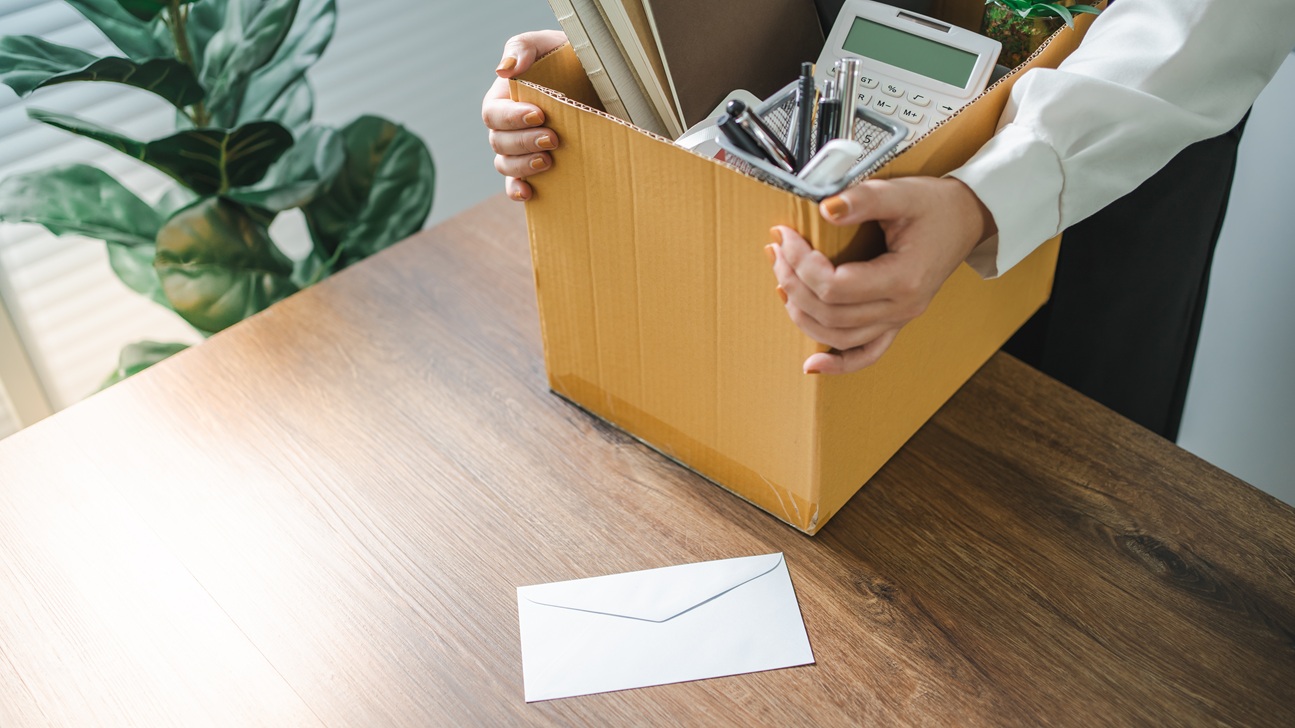 Manos que sostienen caja con artículos de oficina